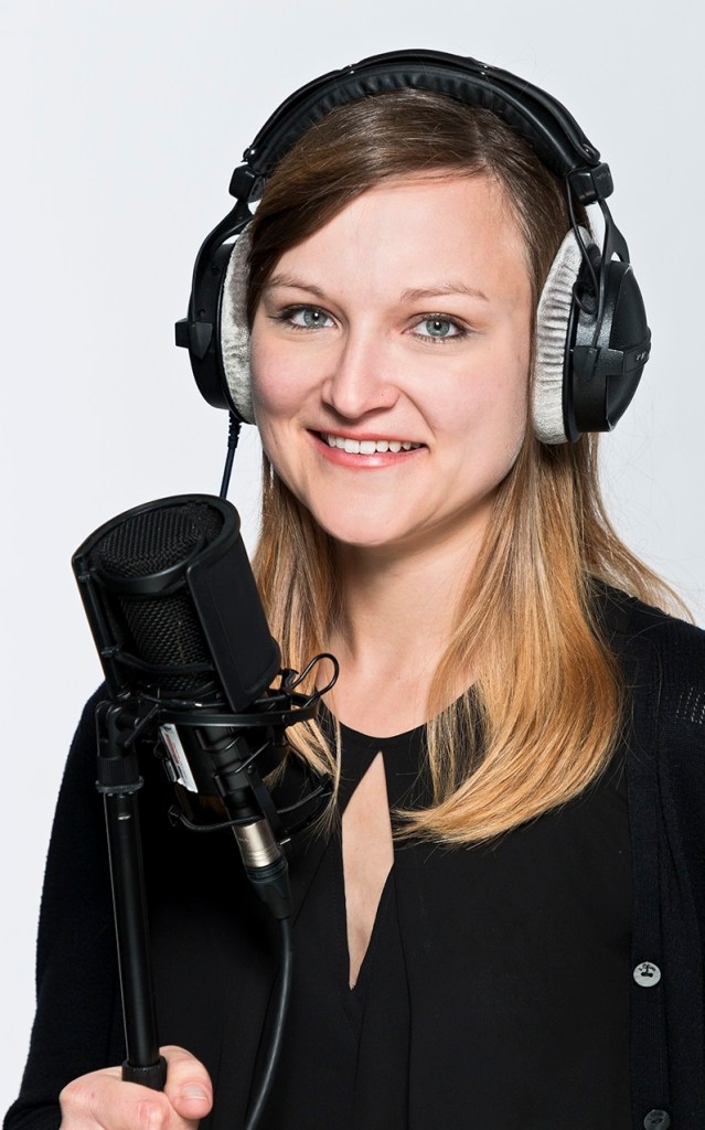 Foto von Lisa Fritsch mit Mikrofon in der Hand und Kopfhörern auf den Ohren.